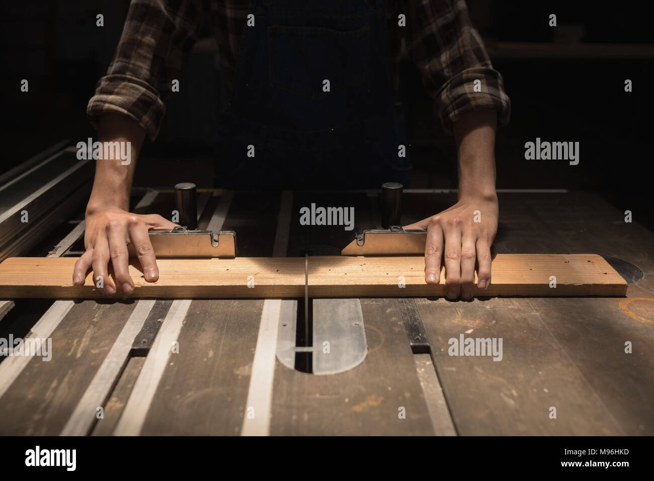 Female welder measuring a wooden piece in workshop Stock Photo