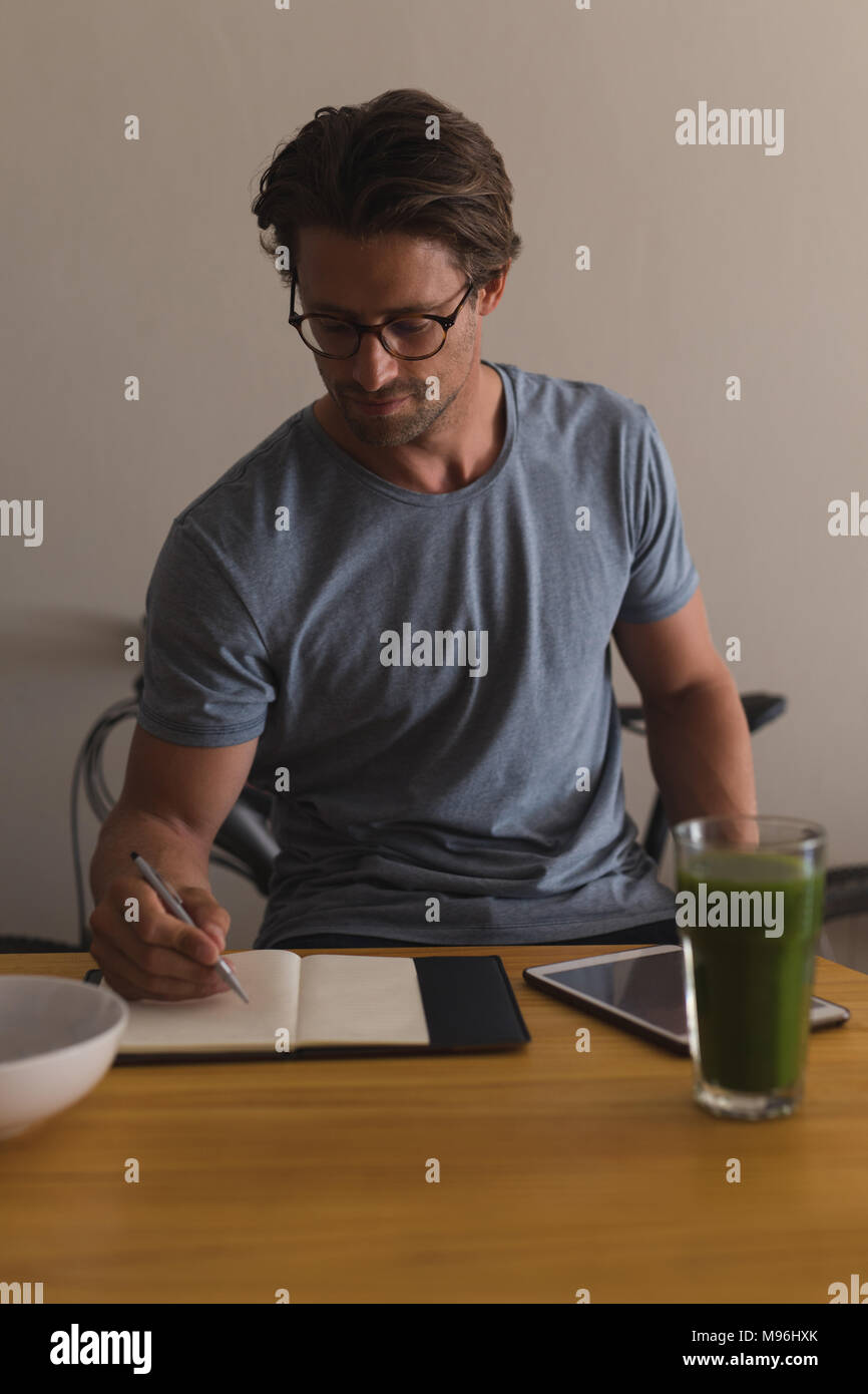 Man writing on a diary in living room Stock Photo