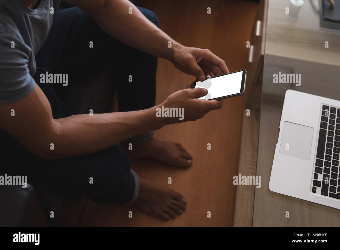 Man using mobile phone in living room Stock Photo