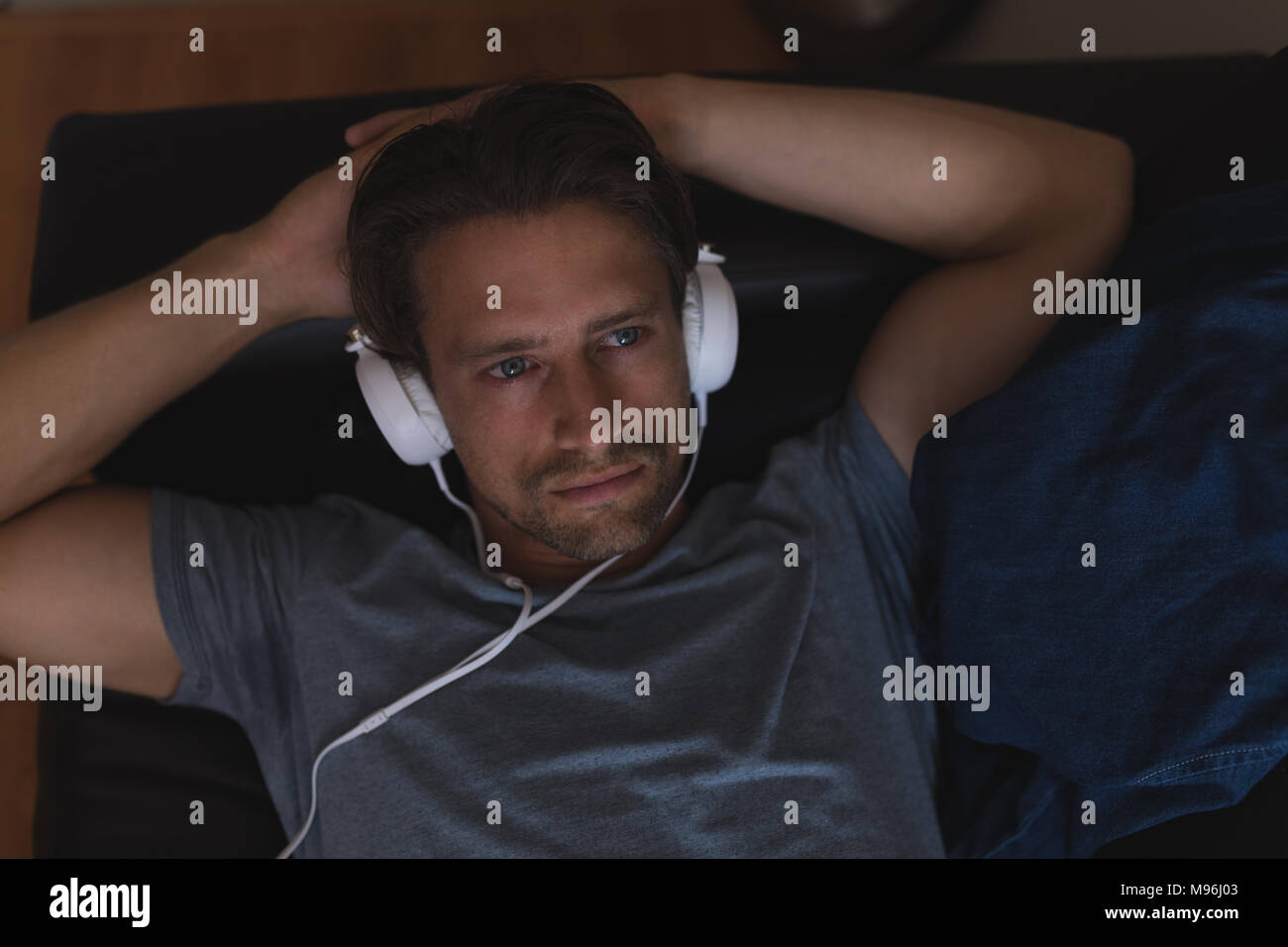 Man listening music on headphones in living room Stock Photo