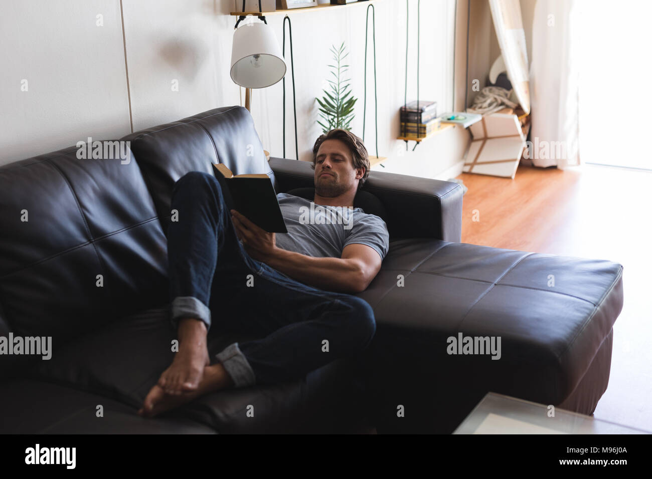 Man reading a book in living room Stock Photo