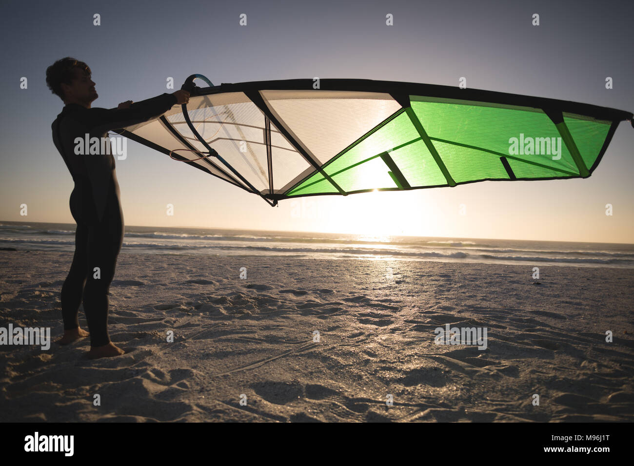 Male surfer holding a kite on the beach Stock Photo