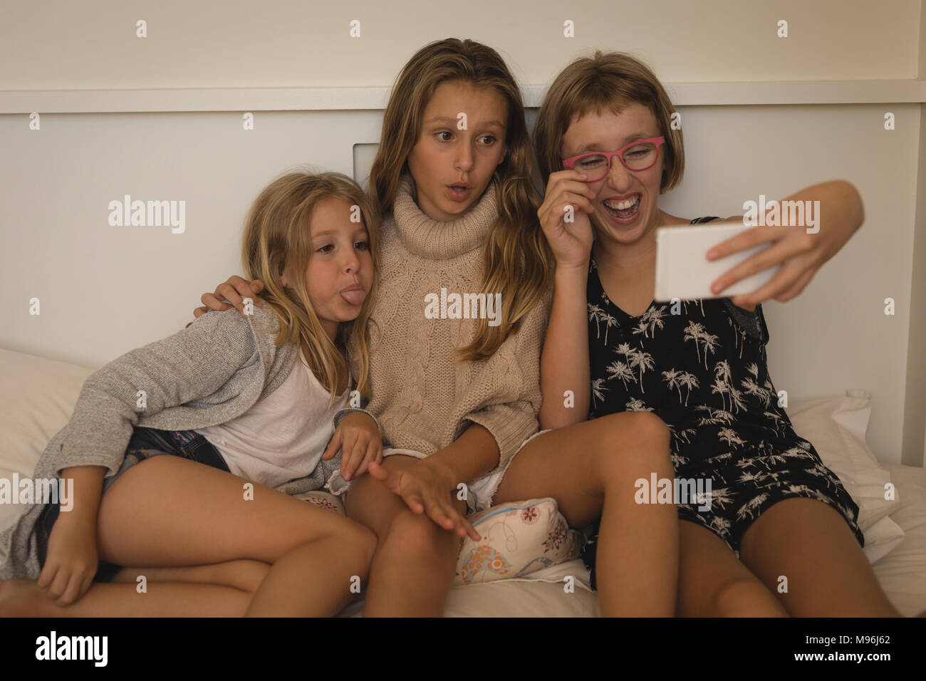 Siblings taking selfie with mobile phone in bedroom Stock Photo