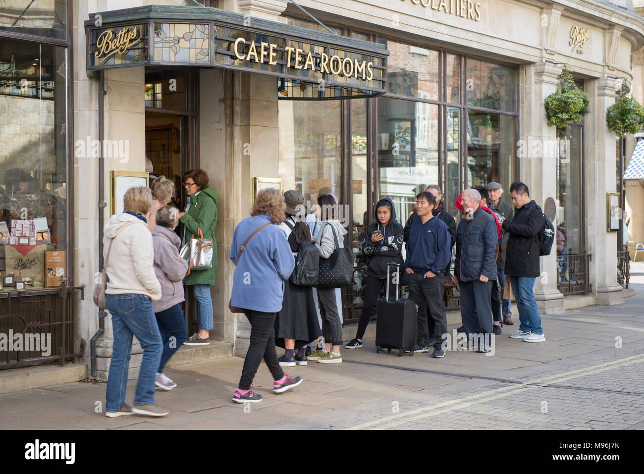 People queuing for afternoon tea outside Bettys Cafe and Tea Room St Helen's Square York UK Stock Photo
