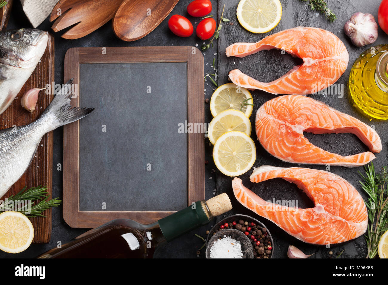 Raw salmon fish fillet and dorado with spices cooking on cutting board ...