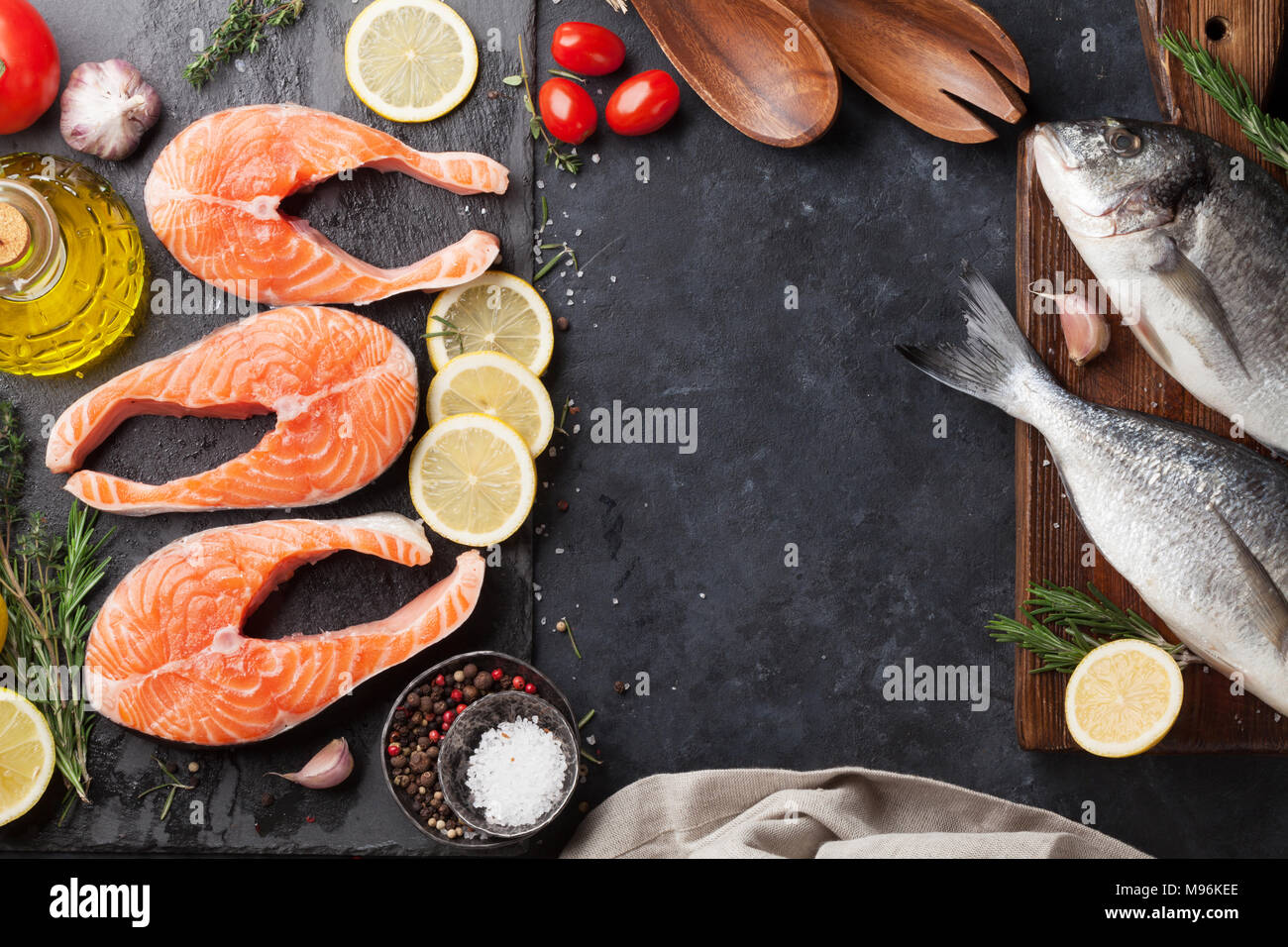 Raw salmon fish fillet and dorado with spices cooking on cutting board ...