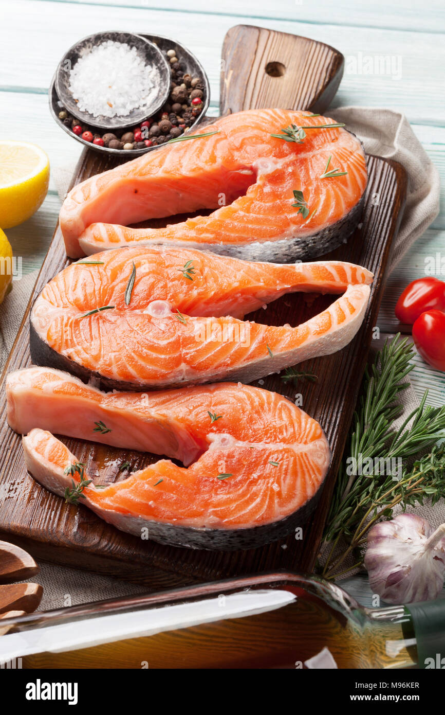 Raw salmon fish steaks with spices cooking on cutting board. Top view ...