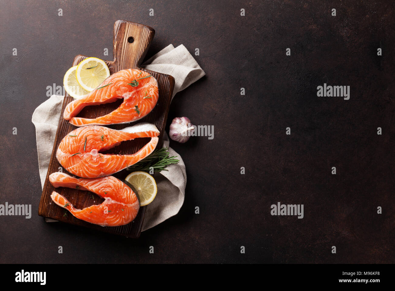 Raw salmon fish steaks with spices cooking on cutting board. Top view ...