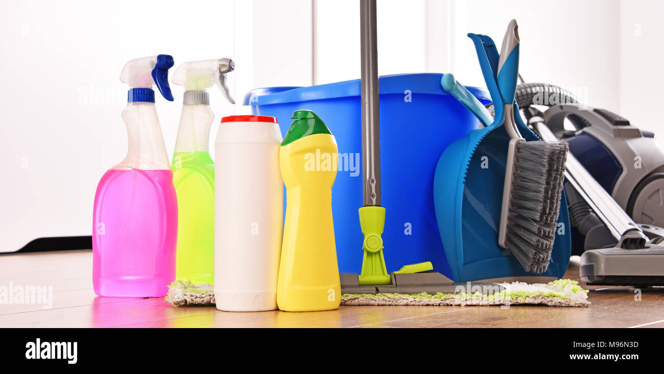 Vacuum cleaner and variety of detergent bottles and chemical cleaning supplies on the floor Stock Photo