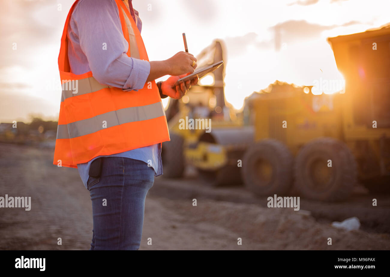 Asian engineer with hardhat using  tablet pc computer inspecting and working at construction site Stock Photo