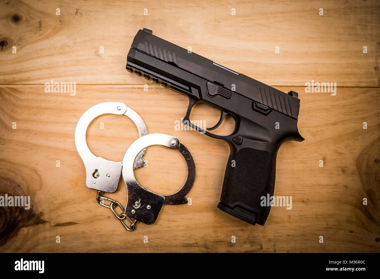 Hand gun with hand cuffs on wooden surface concept Stock Photo