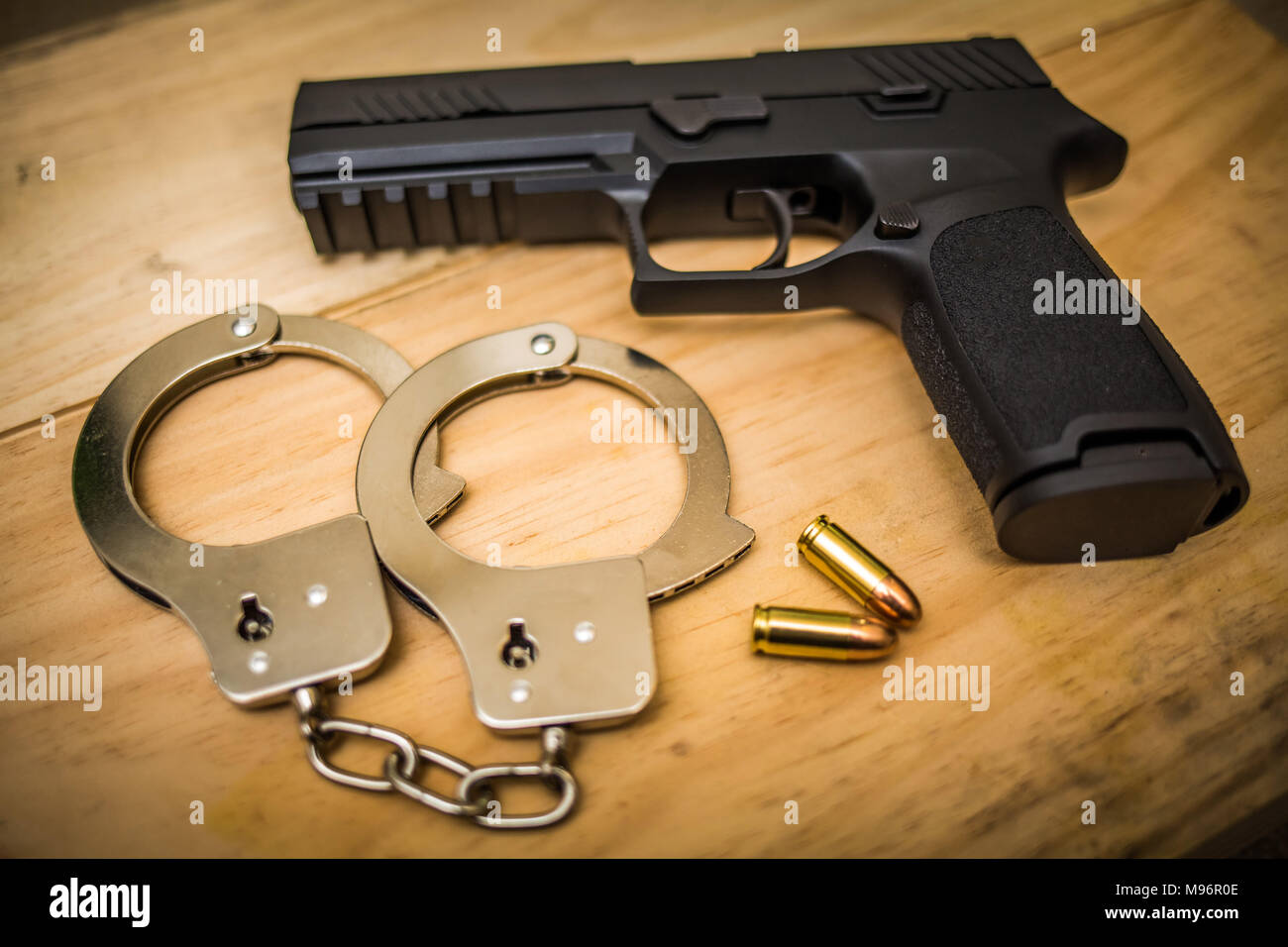 Hand gun with hand cuffs on wooden surface concept Stock Photo
