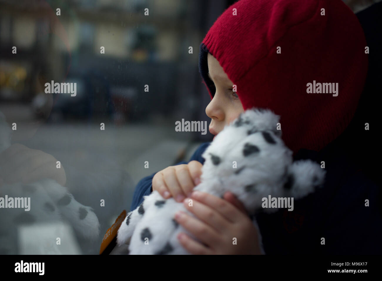 Child Holding Soft Toy Travelling on Bus, Looking out of Window Stock Photo