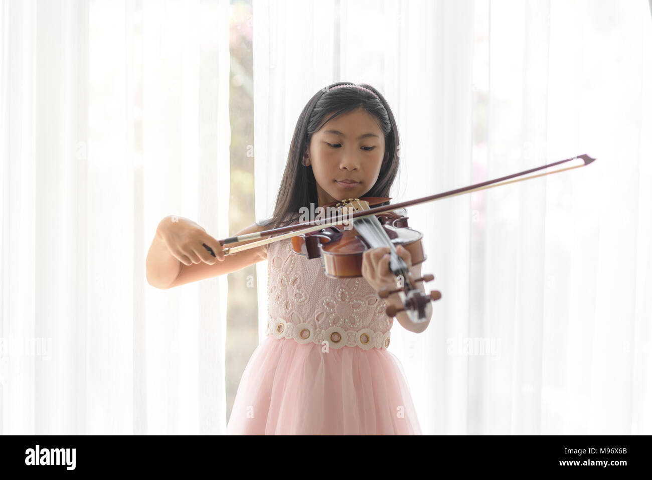 Cute girl playing violin near window at home Stock Photo - Alamy