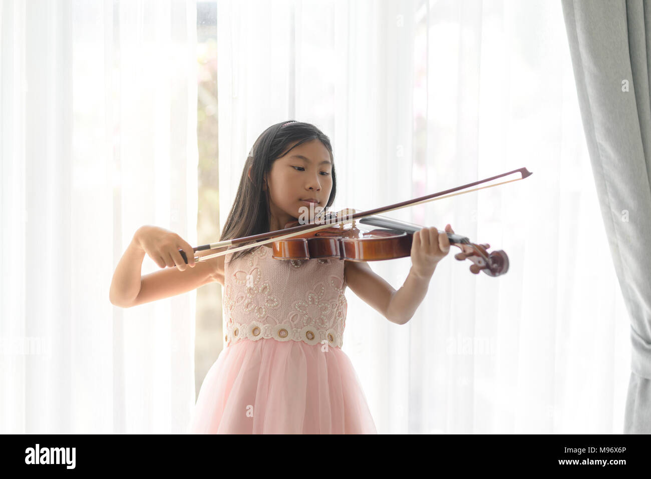 Cute girl playing violin near window at home Stock Photo - Alamy