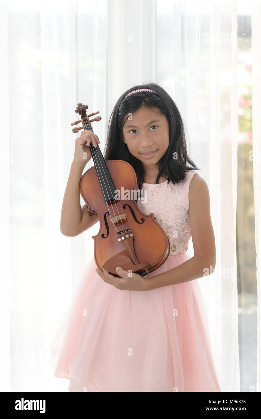 Cute girl holding violin near window at home Stock Photo - Alamy