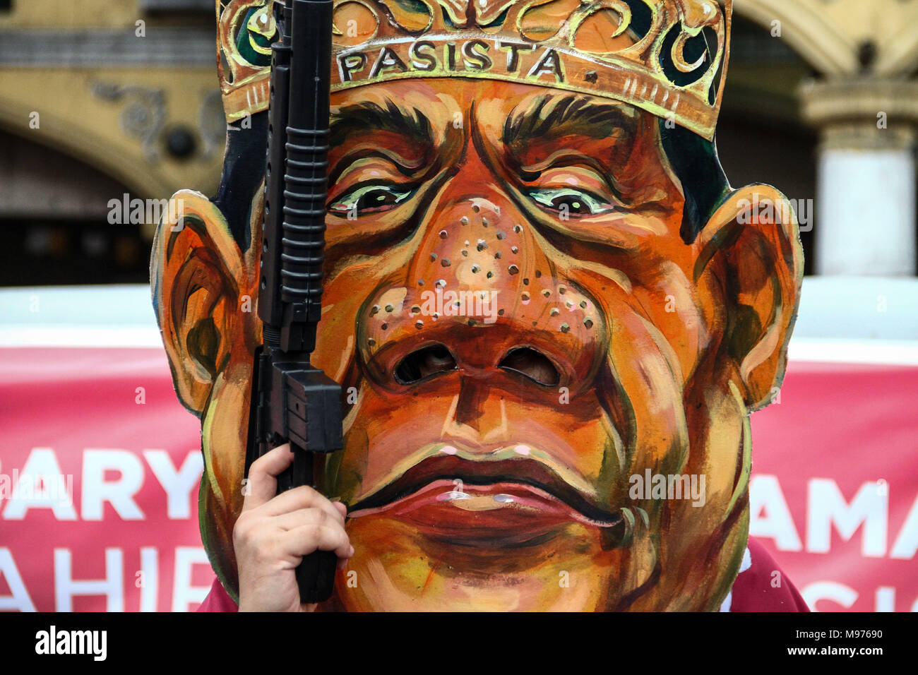 Manila, Philippines. 23rd March, 2018. A protester wearing a President Duterte mask holds a toy rifle in Plaza Miranda, Manila. Activists slammed Duterte for the alleged double standard in his war on drugs, the crackdown on activists, and the recent designation of activists as terrorists according to the Malacanang. The March was held a few days before the Holy Week, with protesters carrying a cross to Mendiola, Manila. Credit: SOPA Images Limited/Alamy Live News Stock Photo