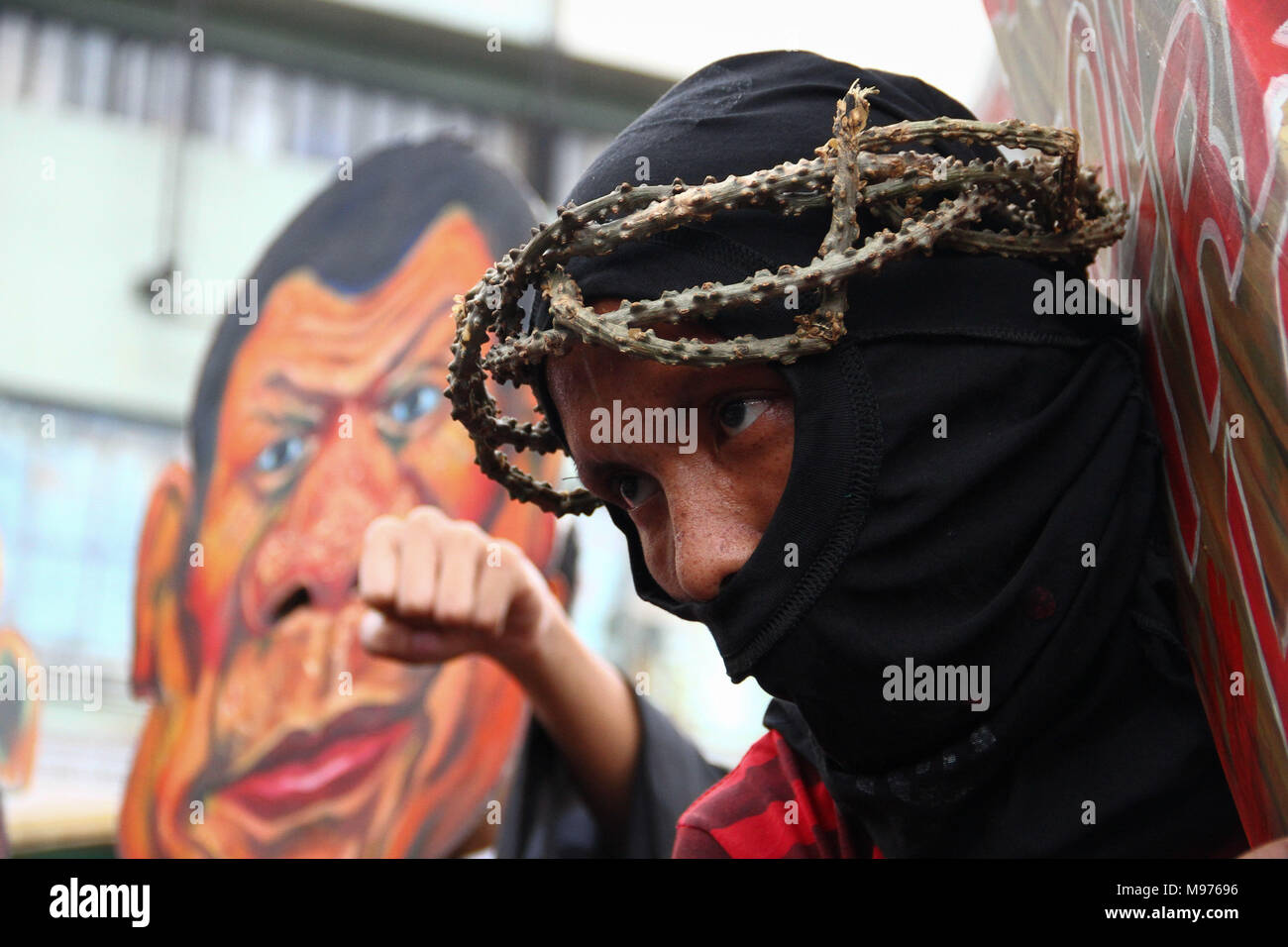 Manila, Philippines. 23rd March, 2018. A protester seen carrying a cross as he March towards Mendiola bridge in Manila. Activists slammed Duterte for the alleged double standard in his war on drugs, the crackdown on activists, and the recent designation of activists as terrorists according to the Malacanang. The March was held a few days before the Holy Week, with protesters carrying a cross to Mendiola, Manila. Credit: SOPA Images Limited/Alamy Live News Stock Photo