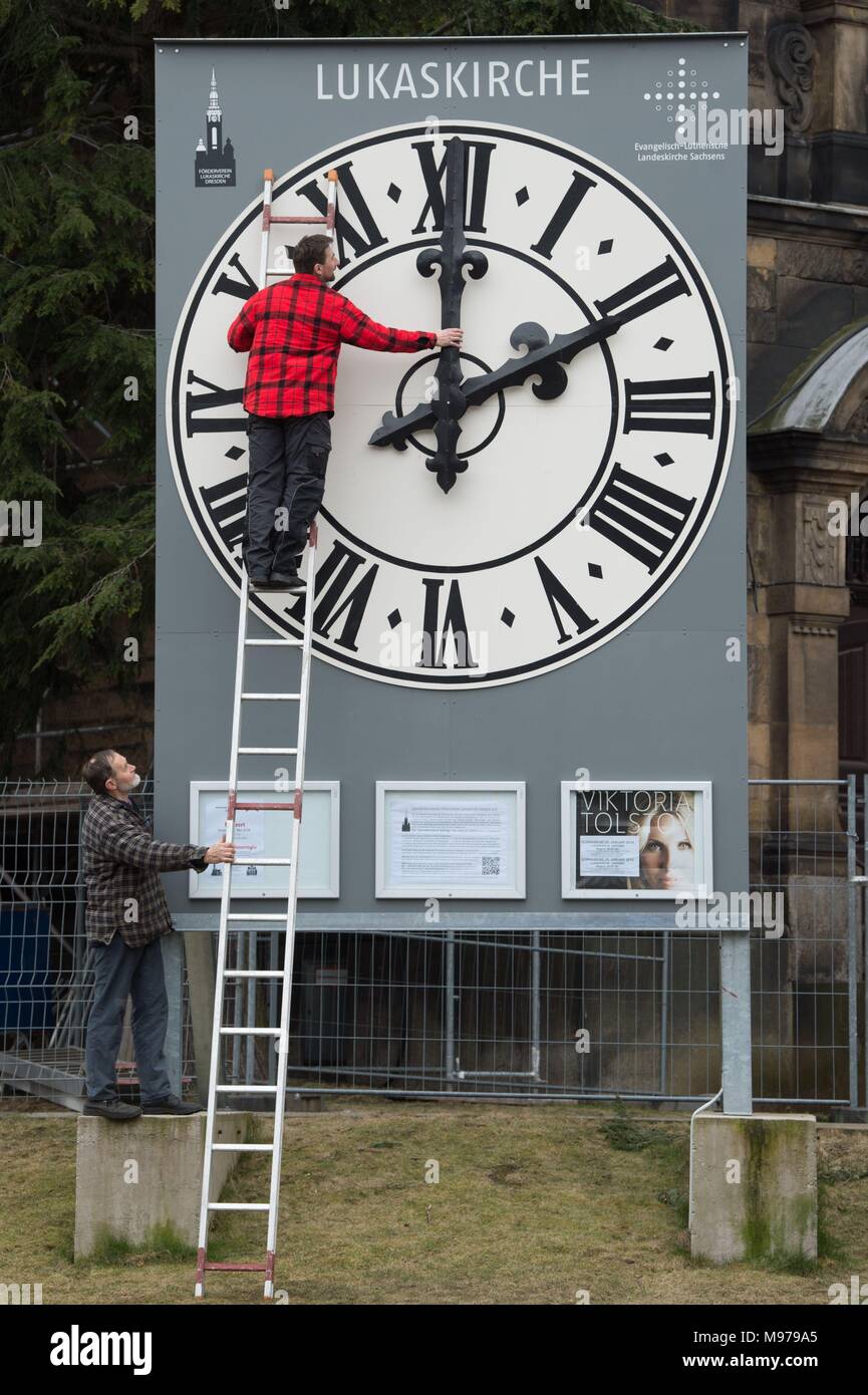 23 March 2018, Germany, Dresden: Clock technician Tobias Vogler (top) and his father Andreas Vogler check the mechanics of the church-clock's hands of the Dresden Lukas Church. Due to construction works at the church the clock is at ground level. The summertime in Germany begins on the coming weekend. Photo: Sebastian Kahnert/dpa-Zentralbild/dpa Stock Photo