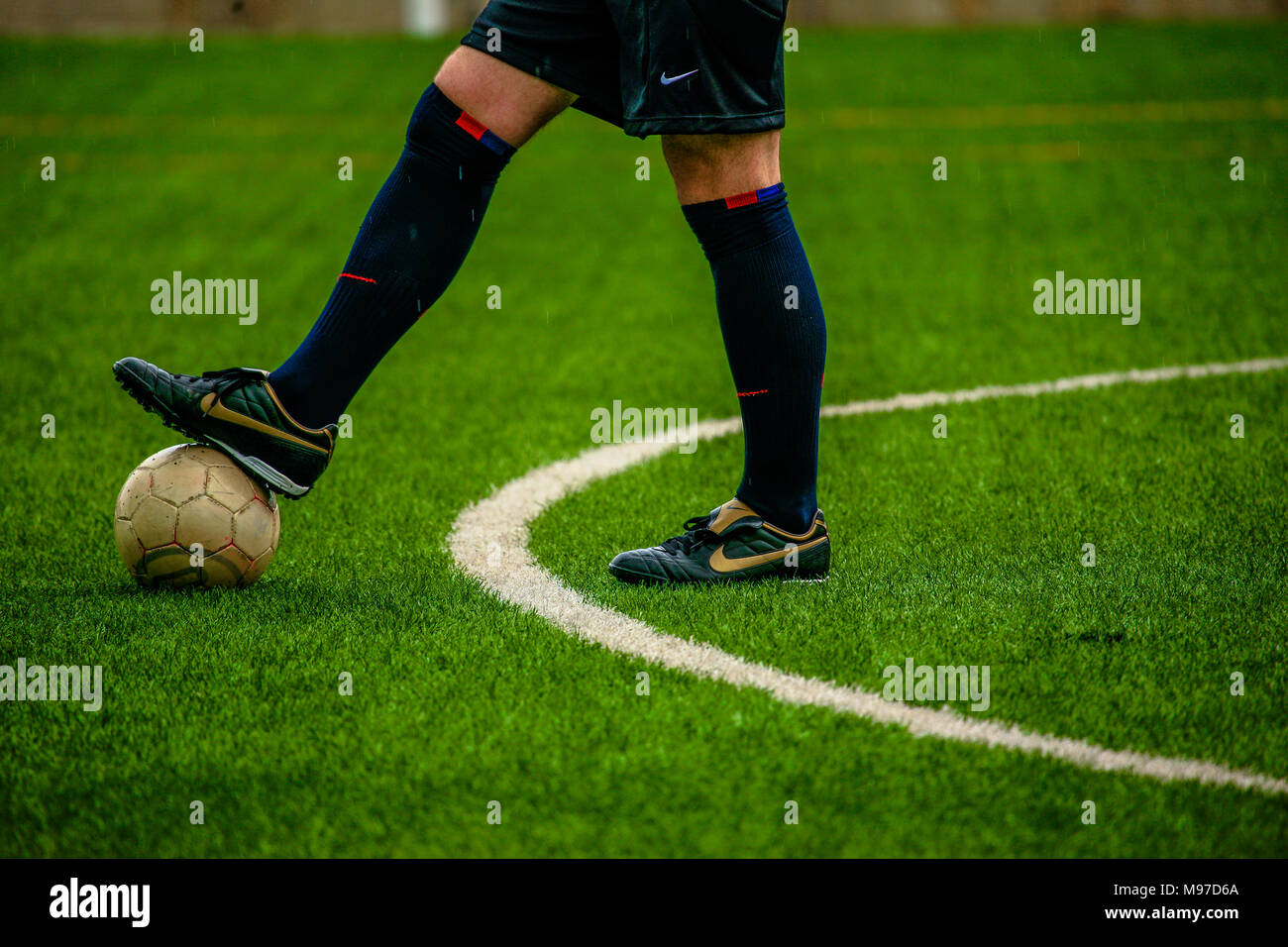 A referee in black uniform with is boot touching the ball is about to start the match, Barcelona, Spain Stock Photo