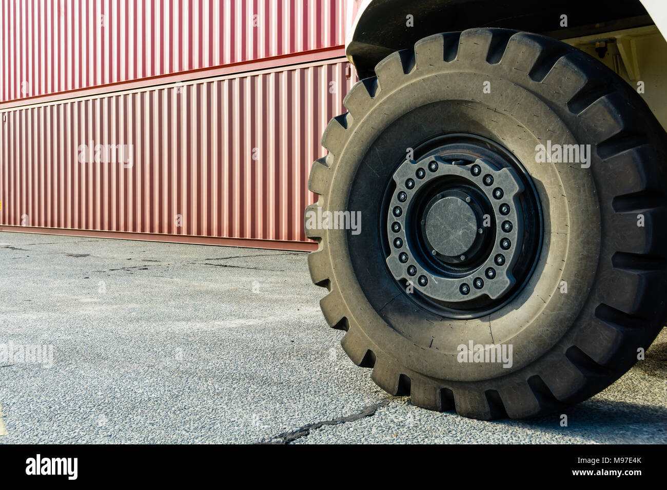 Wheel of a reach stacker and stacked containers in a shipping yard in