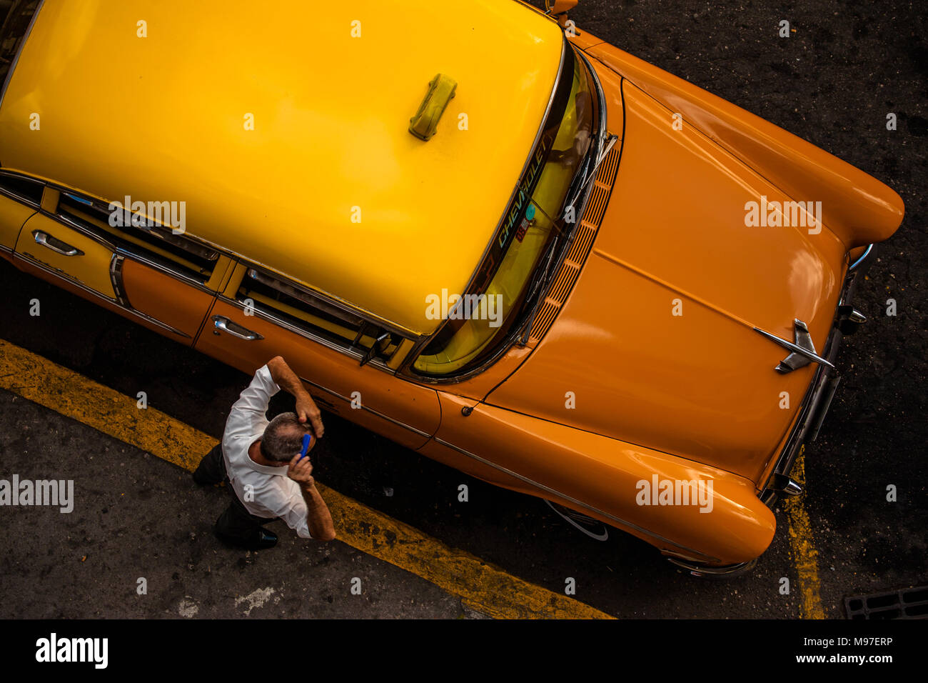 A taxi driver combs his hair while waiting for his customer to arrive, Havana, Cuba. Stock Photo