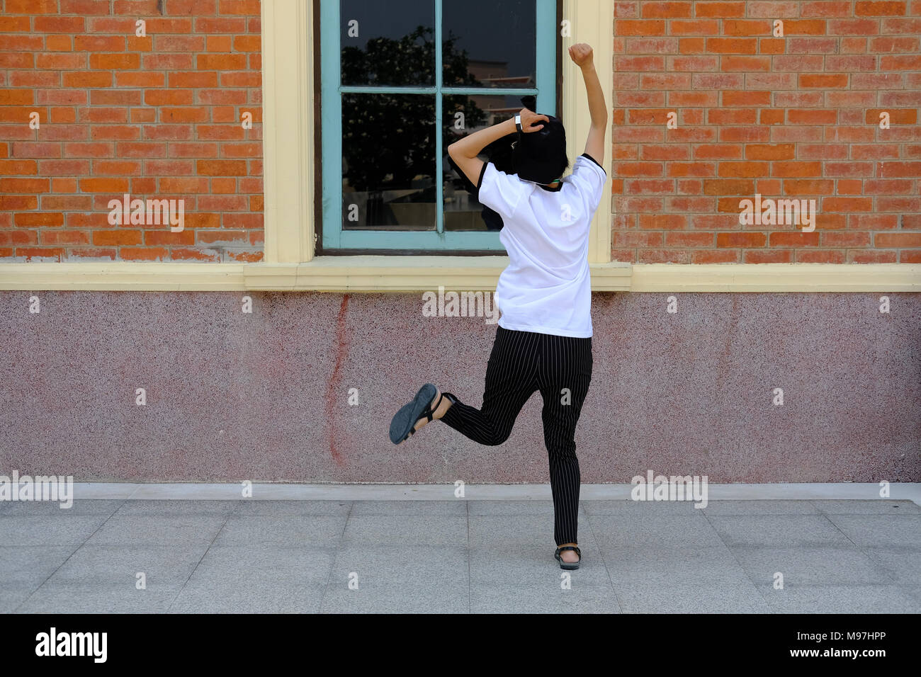 backside of woman jumping with happiness outdoors. Stock Photo
