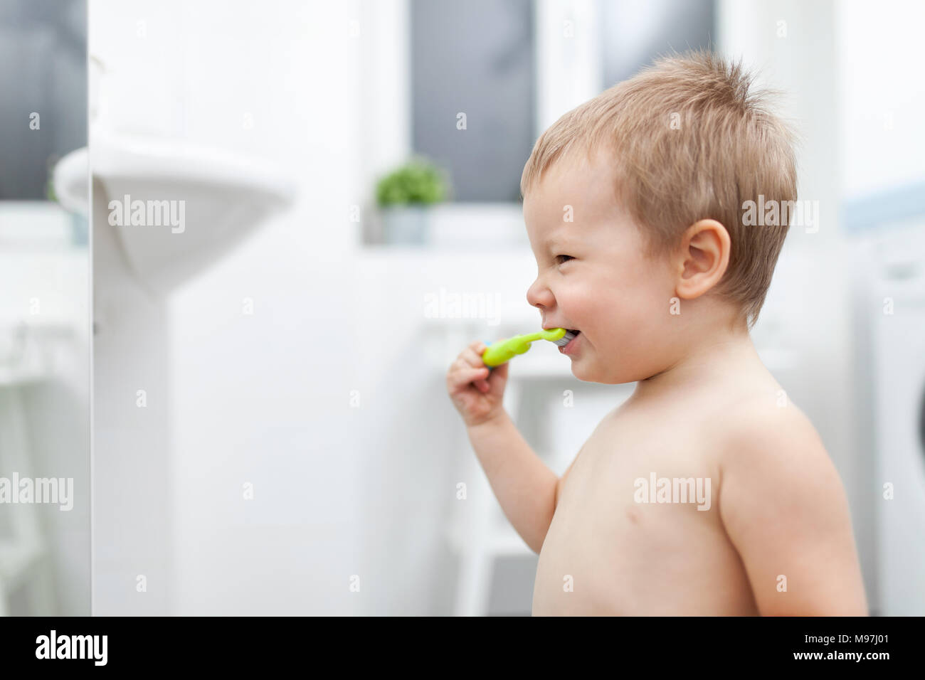 Adorable child learing how to brush his teeth in the bathroom Stock Photo