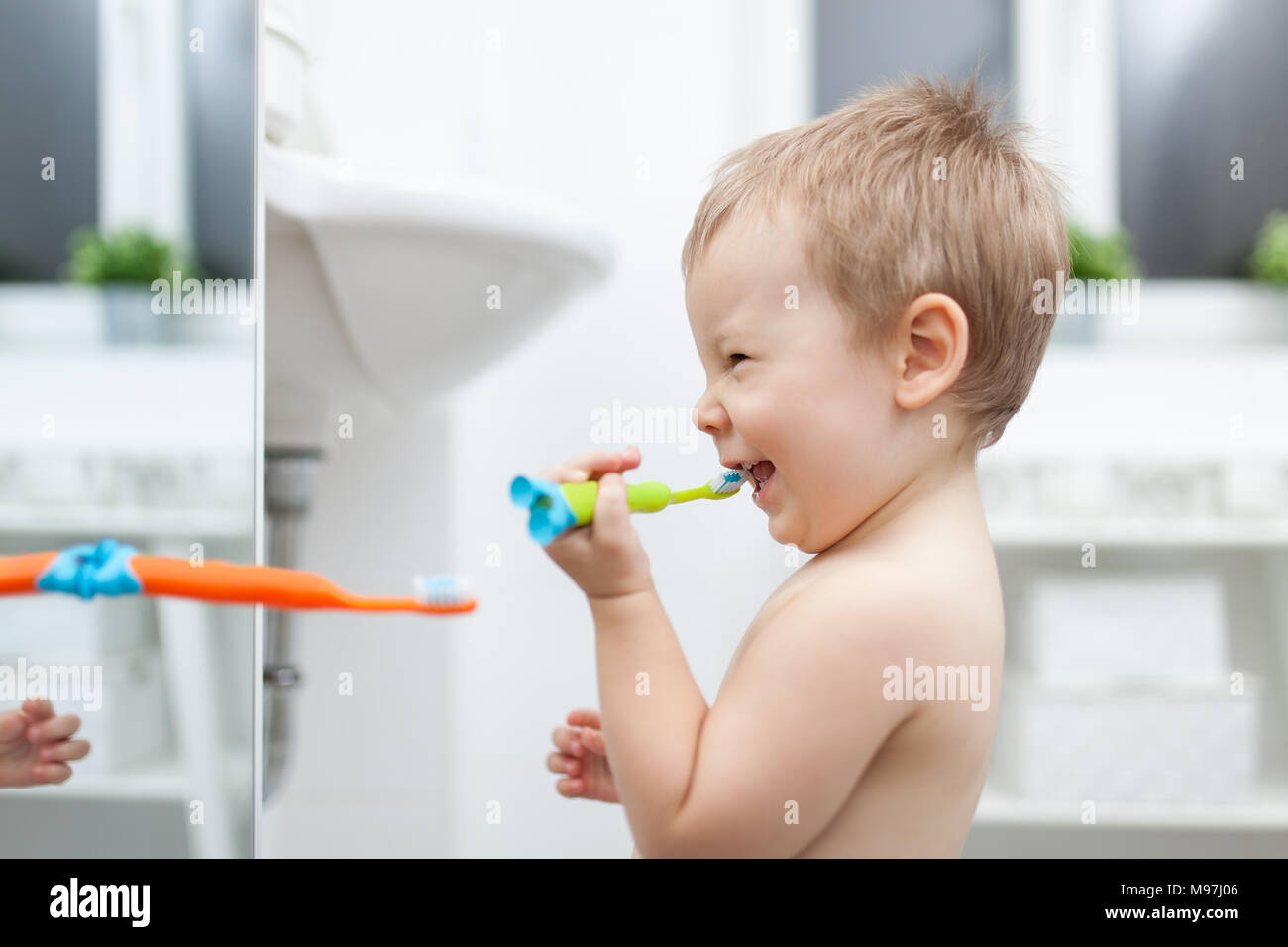 Adorable child learing how to brush his teeth in the bathroom Stock Photo