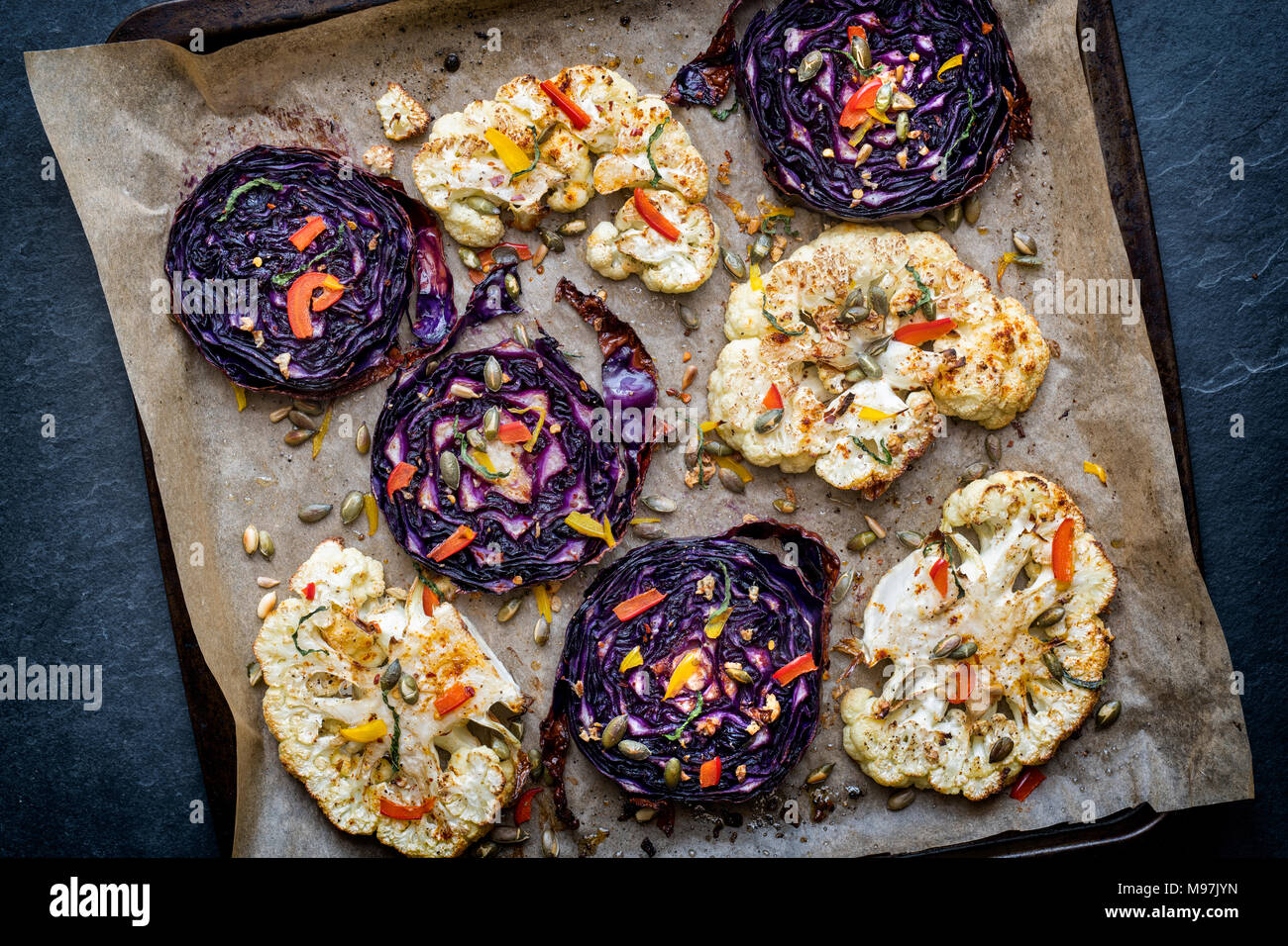 Roasted red cabbage and cauliflower steaks with seeds, chopped pepper, garlic, mint and spices. UK Stock Photo