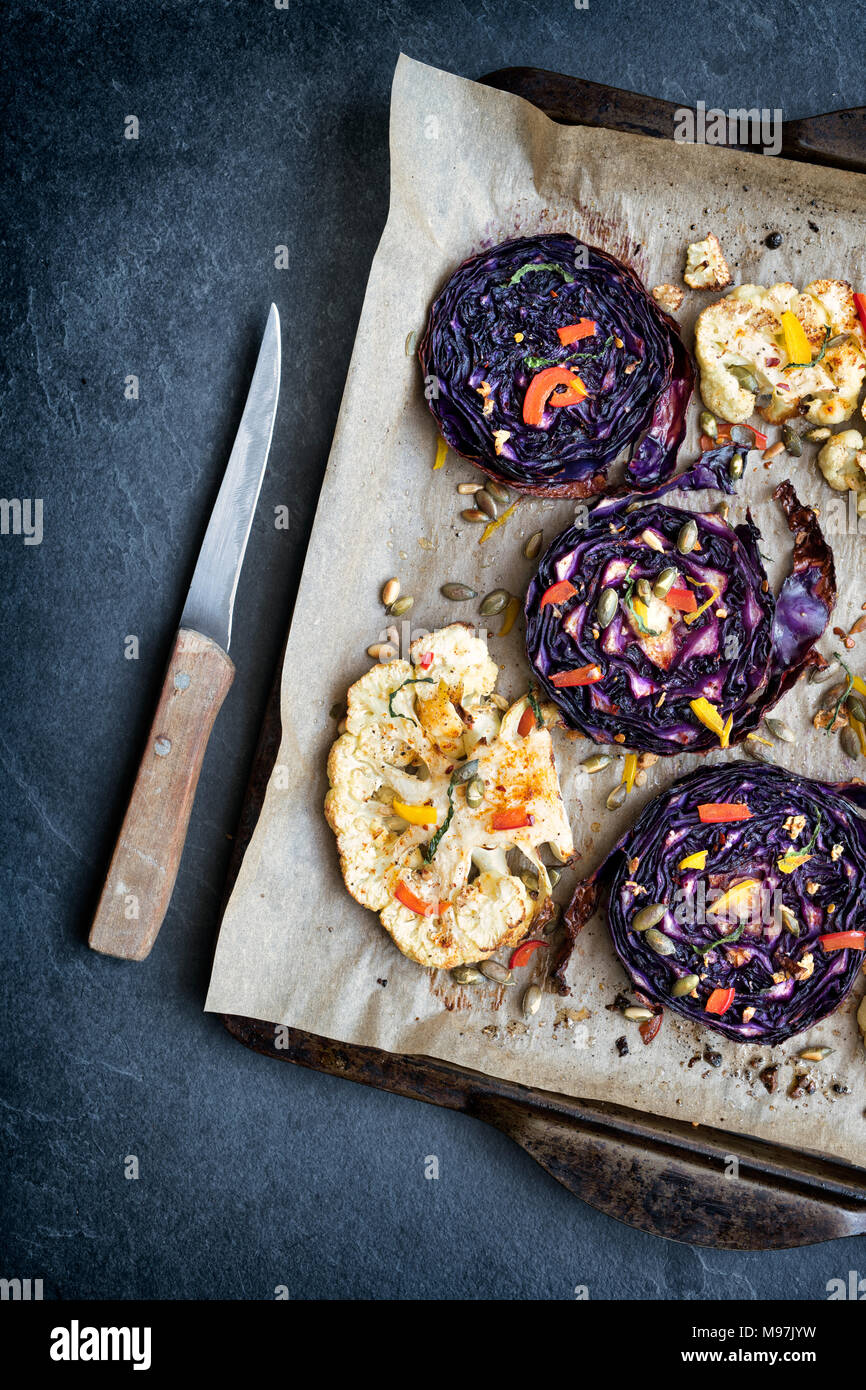 Roasted red cabbage and cauliflower steaks with seeds, chopped pepper, garlic, mint and spices. UK Stock Photo
