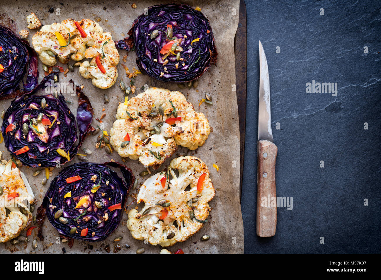 Roasted red cabbage and cauliflower steaks with seeds, chopped pepper, garlic, mint and spices. UK Stock Photo