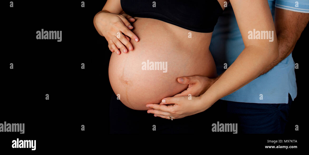 Man hugging his pregnant wife on black background Stock Photo - Alamy