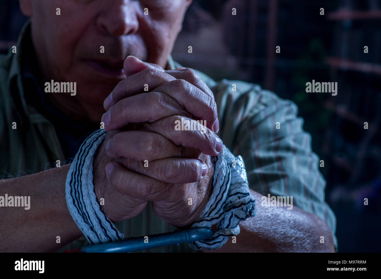 Close up of man hands wrapped with rope around wrists in captivity , victim abused, slave of work, respect for human rights and exploitation concept isolated on blurred background Stock Photo