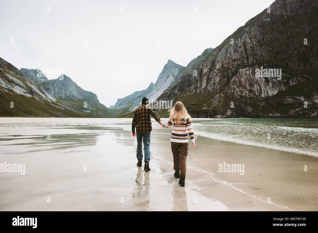 Couple in love holding hands walking on beach in Norway family together traveling Lifestyle concept romantic vacations outdoor Stock Photo