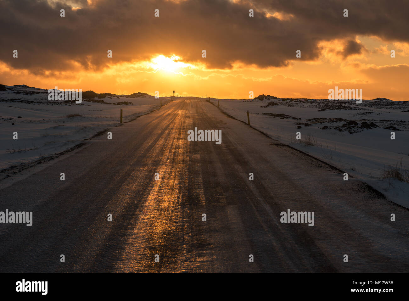 The sunset reflecting on an icy road in Iceland Stock Photo
