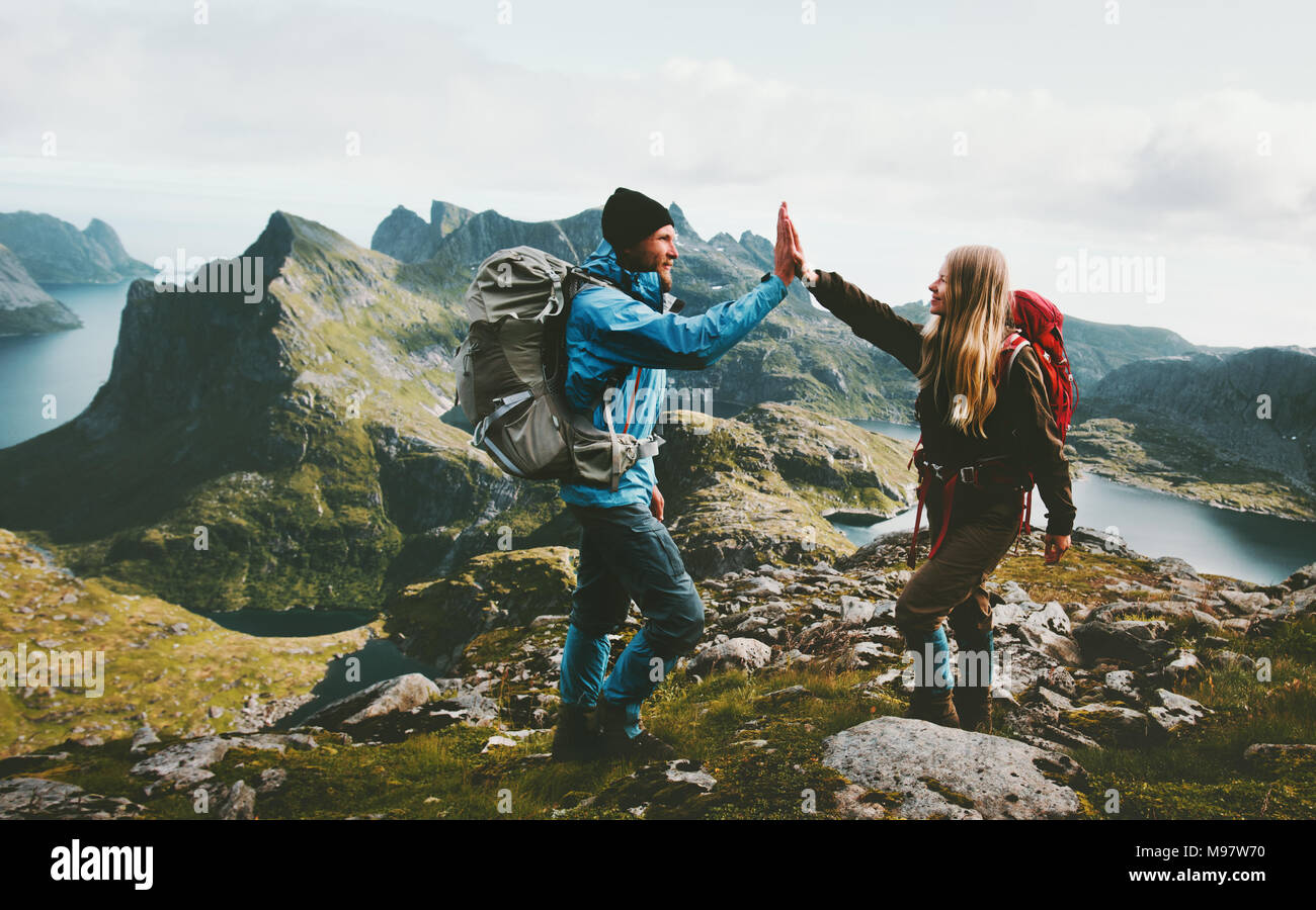 Happy couple giving five hands hiking with backpack in mountains Travel lifestyle adventure concept family together spending active wanderlust vacatio Stock Photo