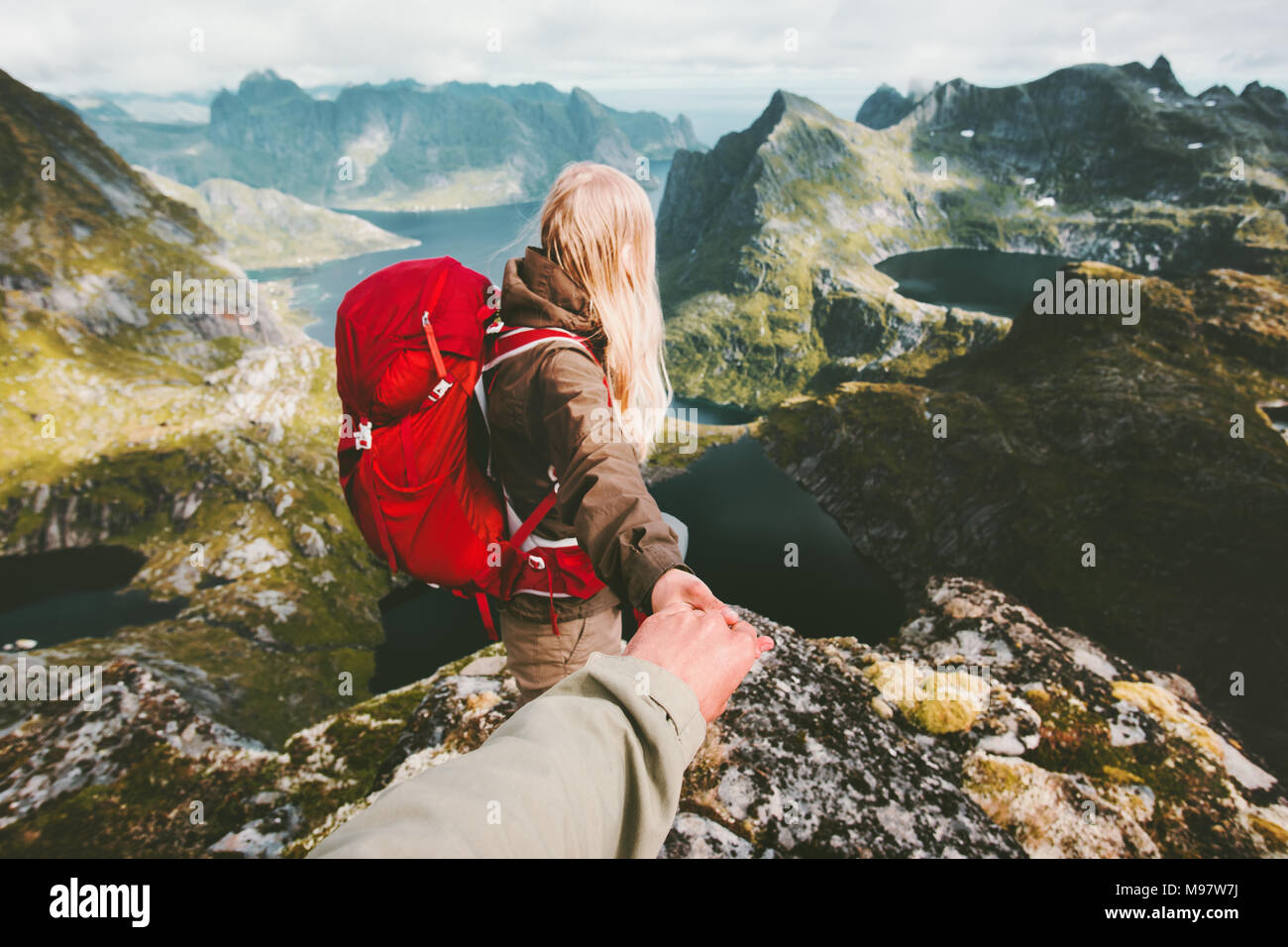Couple travelers follow holding hands in  mountains Norway landscape love and Travel lifestyle concept family traveling active adventure hiking vacati Stock Photo