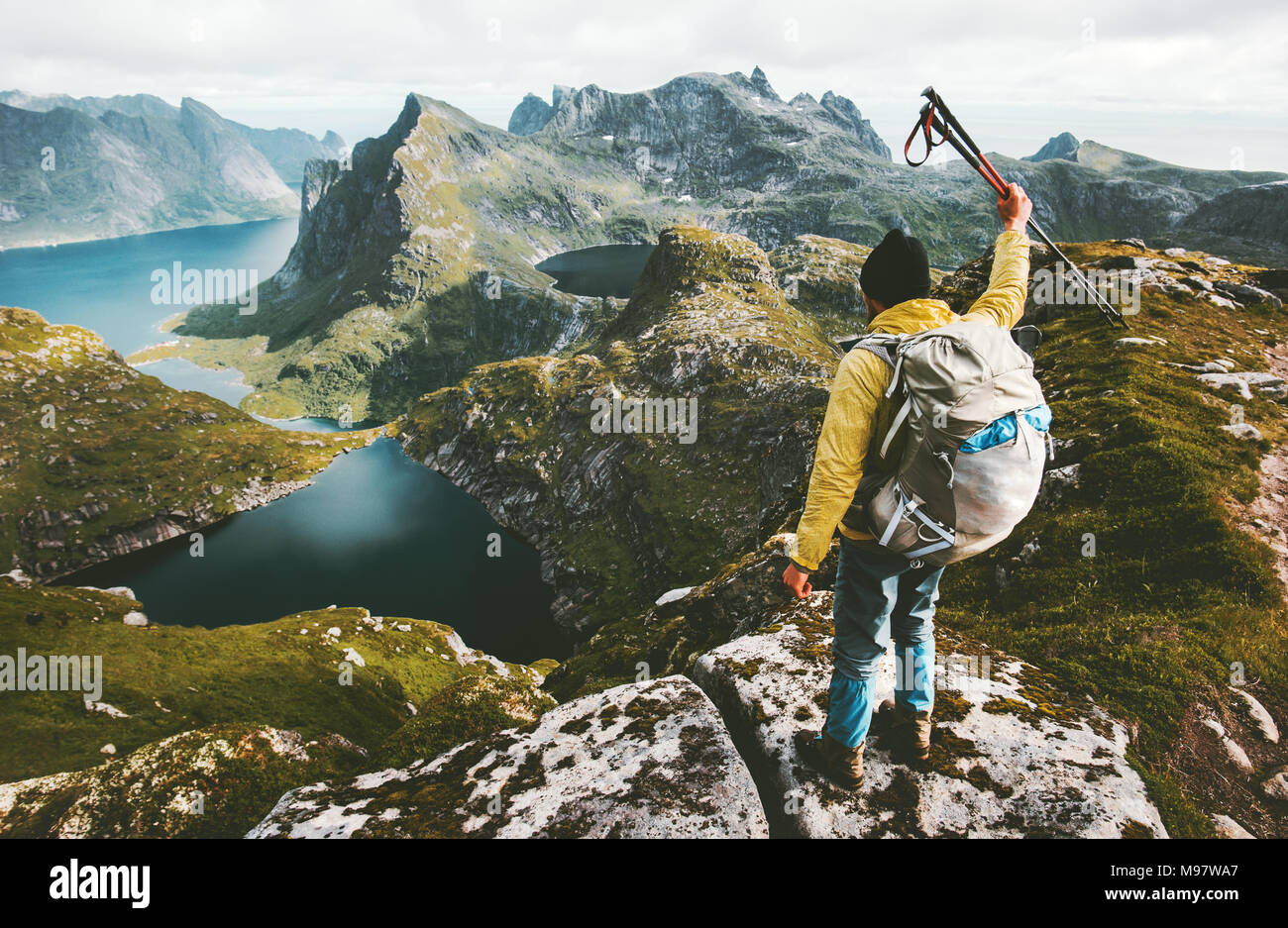Man hiker standing on cliff mountain top raising hand Travel healthy lifestyle adventure concept active summer vacations outdoor Stock Photo
