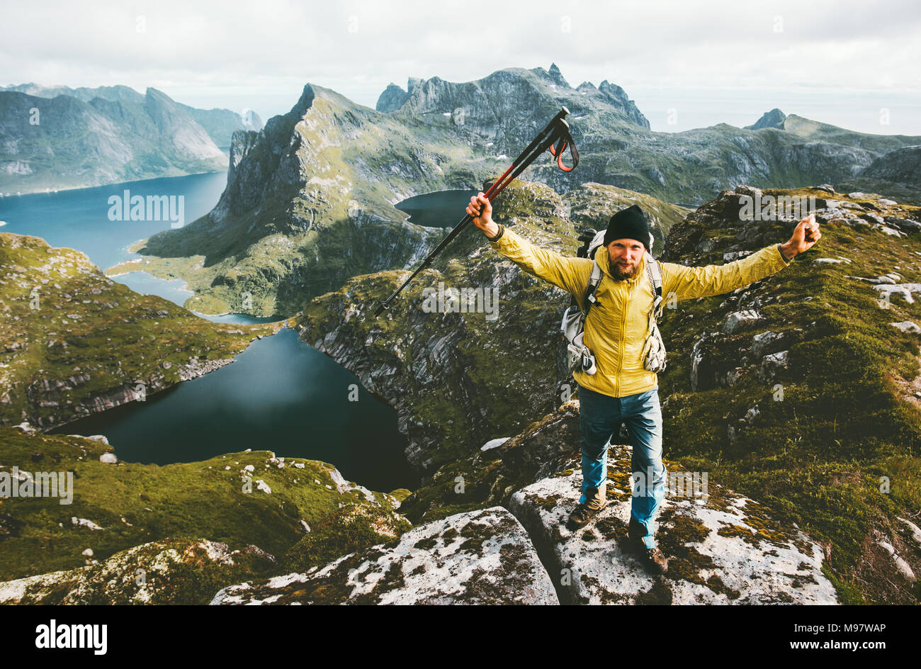 Happy traveler man success raised hands standing on mountain top adventure traveling healthy lifestyle wanderlust concept hiking active summer vacatio Stock Photo
