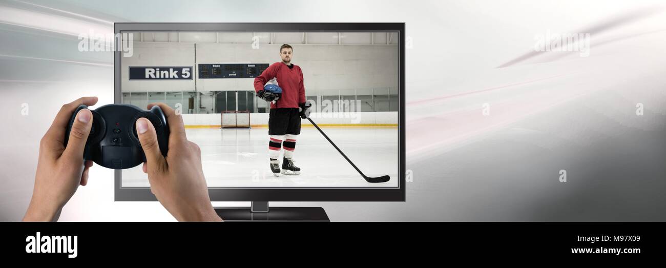 Hands holding gaming controller  with hockey player on television Stock Photo
