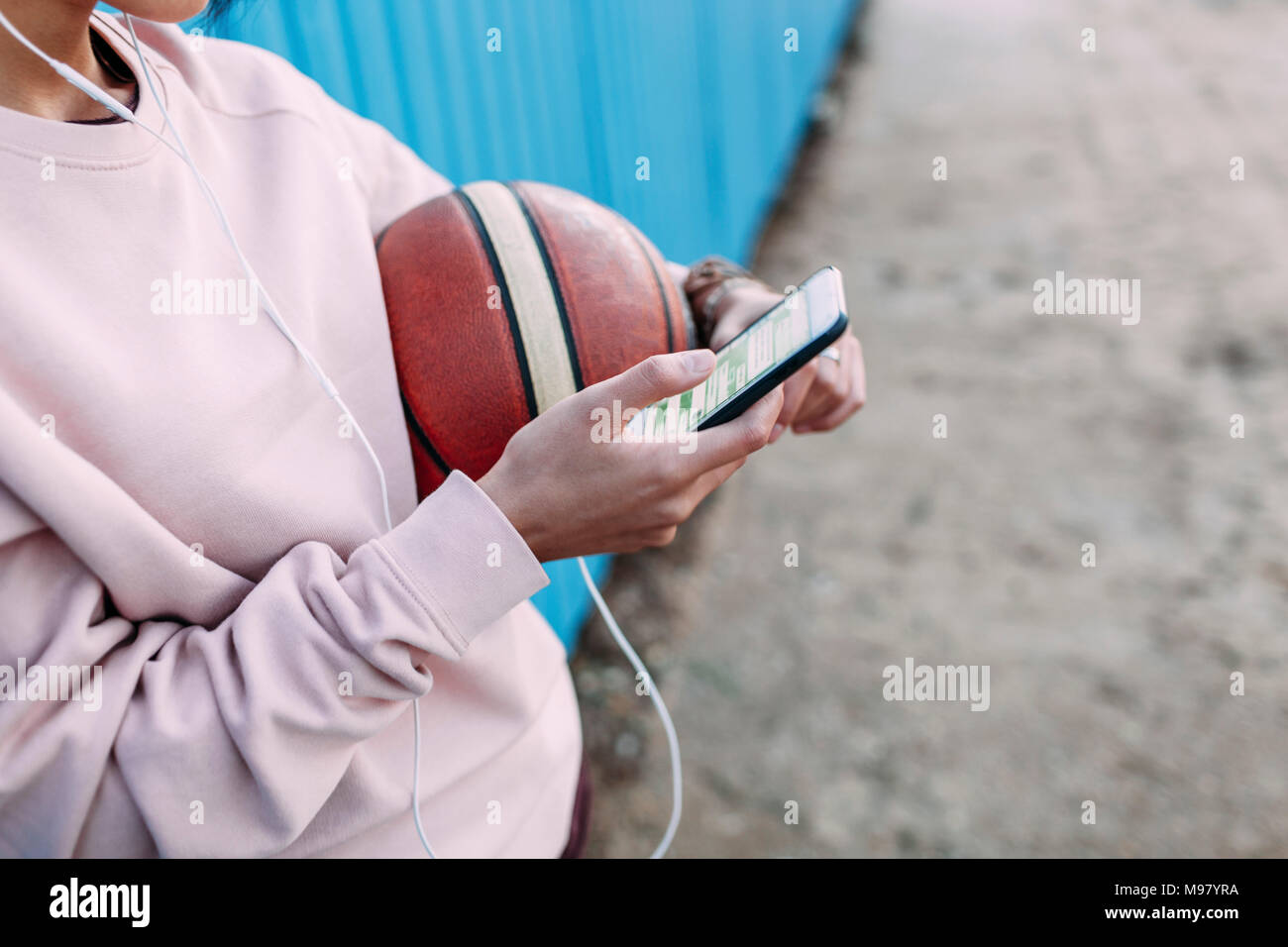 Close-up of woman with basketball, smartphone and earphones Stock Photo
