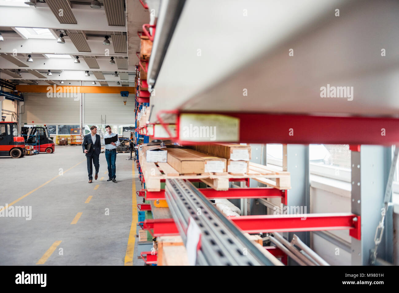 Two men walking and talking in factory shop floor Stock Photo - Alamy
