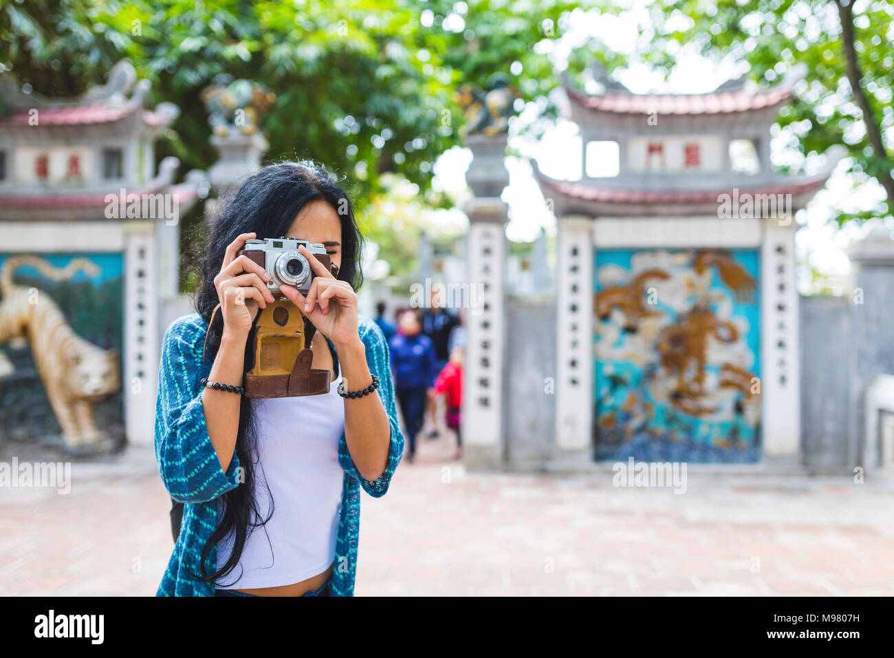 Vietnam, Hanoi, young woman taking a picture with old-fashioned camera Stock Photo