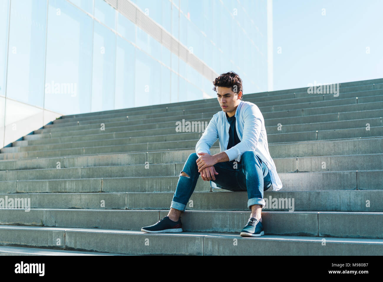 Serious young man sitting on stairs outdoors Stock Photo - Alamy