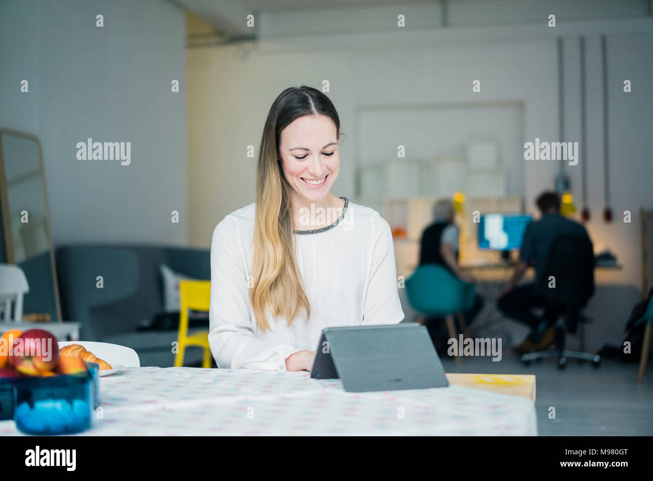 Portrait of smiling young businesswoman working on tablet in a loft Stock Photo