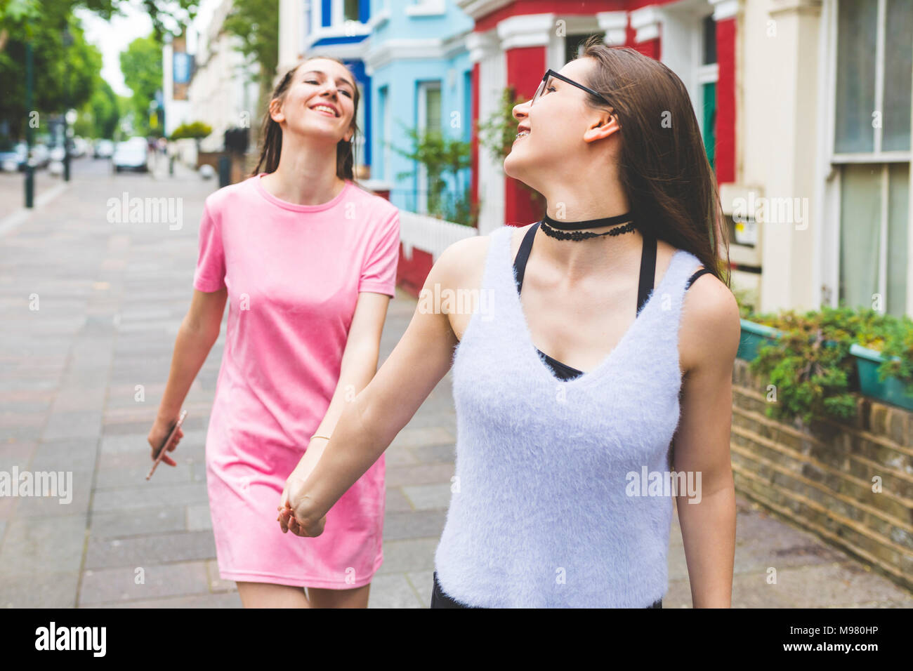 Two happy teenage girls walking hand in hand in the city Stock Photo