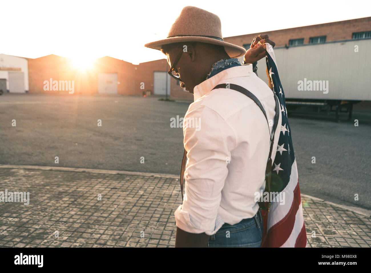 Young man wearing hat and sunglasses holding American flag Stock Photo