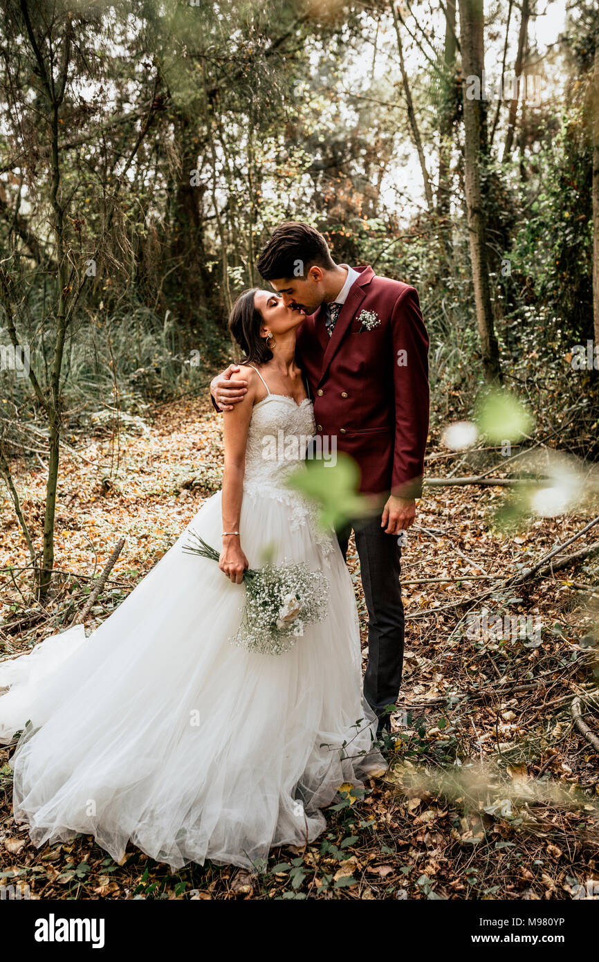 Bride and groom standing in forest kissing Stock Photo - Alamy