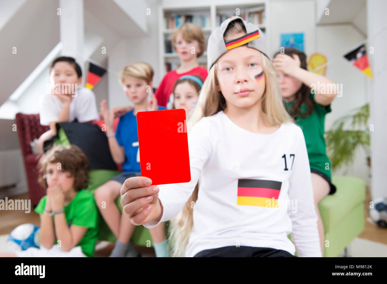 Girl showing red card in front of friends, watching football world cup Stock Photo